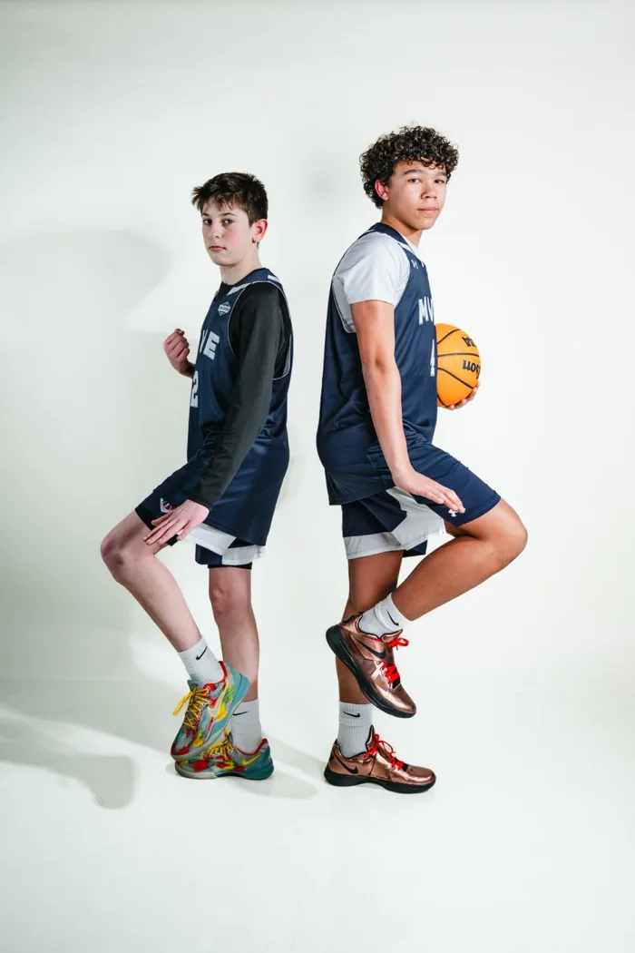 Two MVE teammates back to back with a knee raised, one holding a basketball, at 2026 Media Day